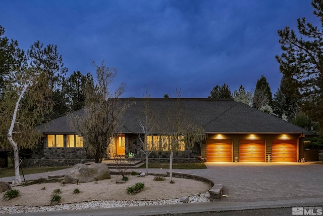 4300 Wild Eagle Ter, Reno, NV 89511 - view of front of house featuring an attached garage, stone siding, decorative driveway, and roof with shingles