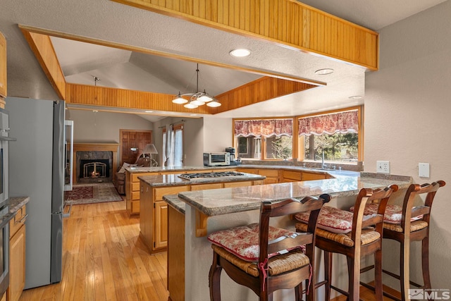 4300 Wild Eagle Ter, Reno, NV 89511 - kitchen with a peninsula, a breakfast bar, light wood-style floors, stone countertops, and vaulted ceiling