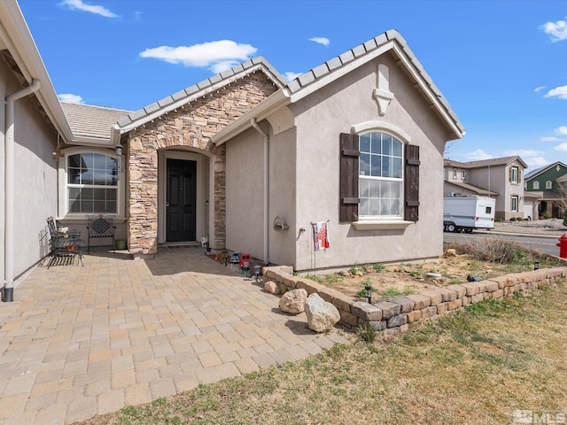 7730 Opal Blf, Reno, NV 89506 - view of front facade with stucco siding, stone siding, a patio, and a tiled roof