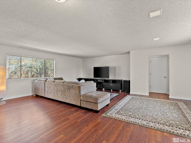 living area with baseboards, a textured ceiling, and wood finished floors