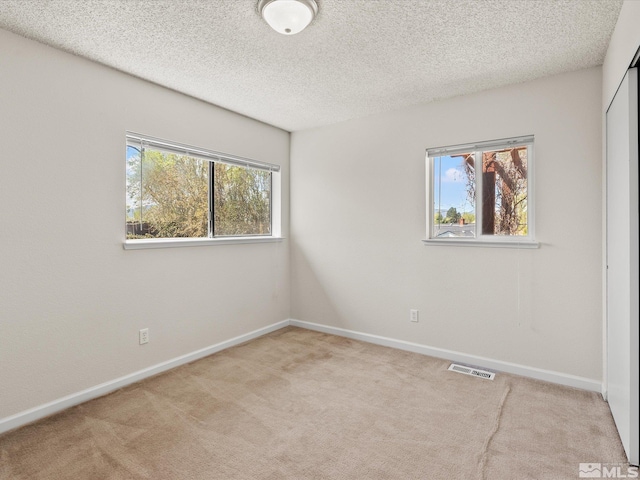 unfurnished room with carpet, baseboards, and a textured ceiling