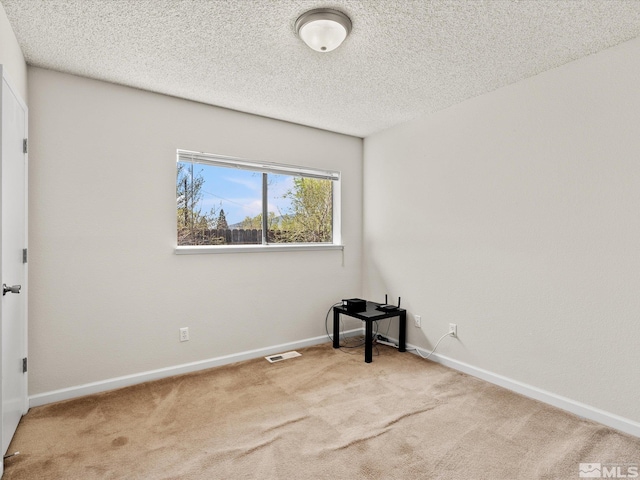 carpeted empty room featuring baseboards and a textured ceiling