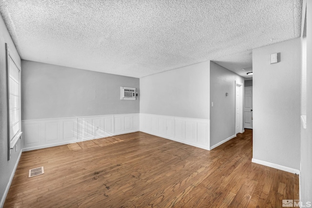 6735 Peppermint Dr, Reno, NV 89506 - empty room featuring wood finished floors, a textured ceiling, wainscoting, and a wall mounted AC
