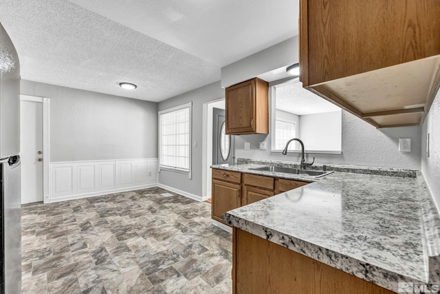 6735 Peppermint Dr, Reno, NV 89506 - kitchen featuring a sink, brown cabinetry, healthy amount of natural light, and a textured ceiling