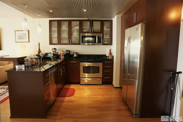 255 N Sierra St Unit 708, Reno, NV 89501 - kitchen with stainless steel appliances, a peninsula, dark countertops, light wood-style flooring, and a sink