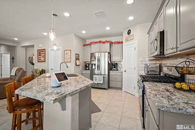 1180 Ferretto Pkwy, Dayton, NV 89403 - kitchen featuring stainless steel appliances, a sink, gray cabinetry, backsplash, and a kitchen bar