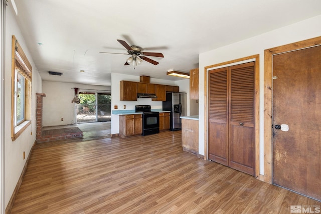 3301 Everett Dr, Reno, NV 89503 - kitchen featuring black range with electric stovetop, stainless steel fridge, light countertops, light wood-type flooring, and brown cabinetry