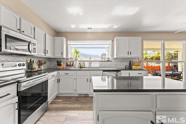 4776 Scenic Hill Cir, Reno, NV 89523 - kitchen featuring appliances with stainless steel finishes, a sink, light wood-style flooring, dark countertops, and tasteful backsplash