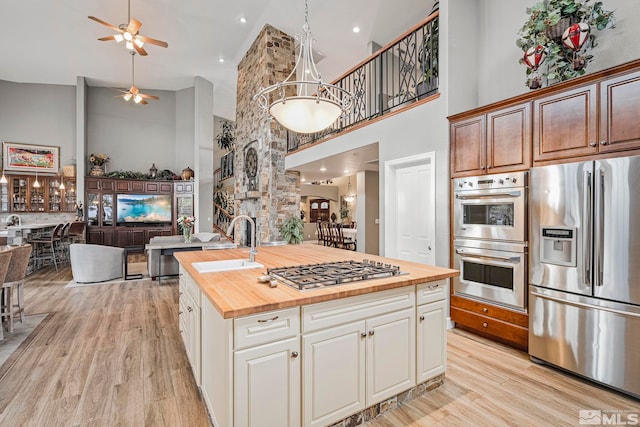 14245 Prairie Flower Ct, Reno, NV 89511 - kitchen with stainless steel appliances, butcher block counters, a towering ceiling, a sink, and open floor plan
