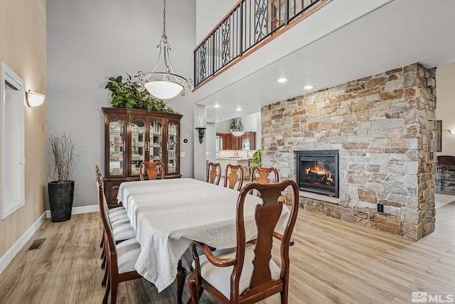 14245 Prairie Flower Ct, Reno, NV 89511 - dining area featuring light wood finished floors, a towering ceiling, a fireplace, and baseboards