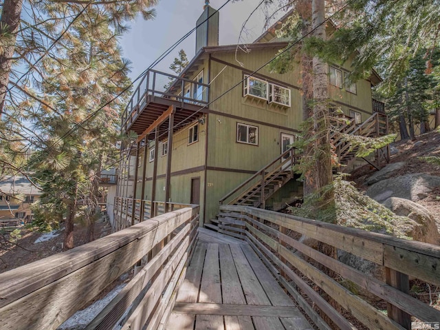 view of property exterior with stairs, a chimney, and a deck
