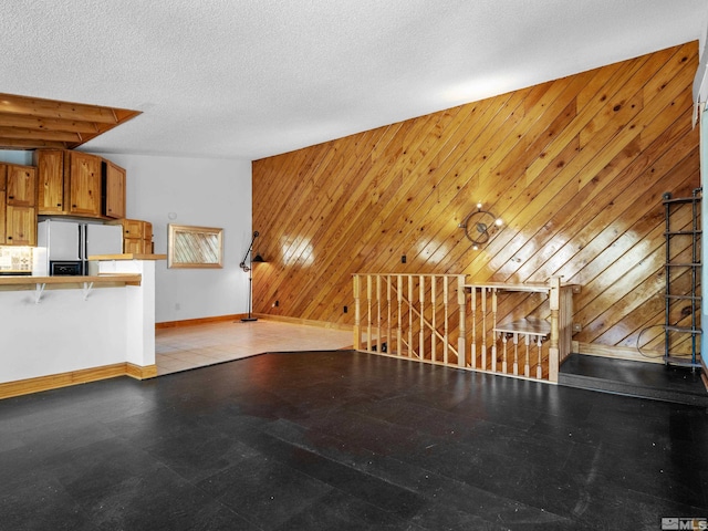 unfurnished living room with baseboards and wooden walls