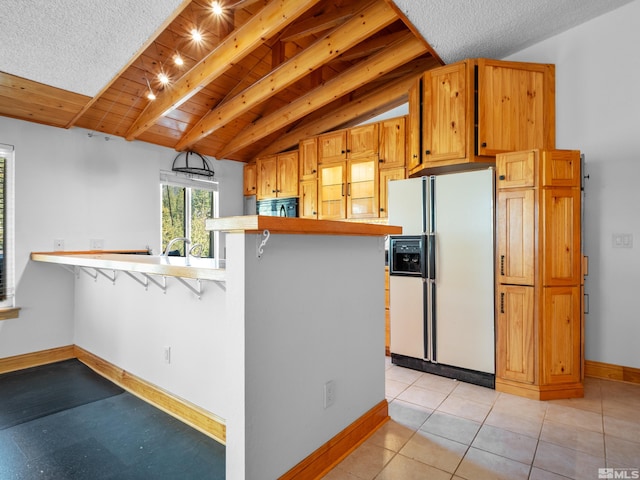 kitchen featuring white fridge with ice dispenser, a kitchen breakfast bar, a peninsula, light countertops, and baseboards