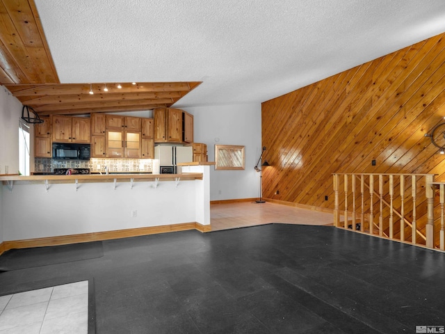 unfurnished living room featuring baseboards and wood walls