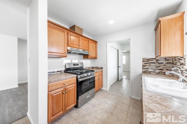 2441 Baxter, Sparks, NV 89431 - kitchen with gas range, under cabinet range hood, a sink, tile countertops, and baseboards