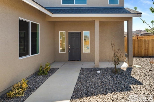 887 Agate, Fernley, NV 89408 - view of exterior entry with stucco siding, fence, roof with shingles, and a patio area