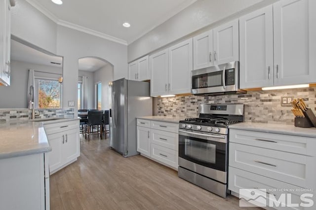 4531 Pyramid Peak Cir, Sparks, NV 89436 - kitchen with stainless steel appliances, a sink, arched walkways, ornamental molding, and white cabinets