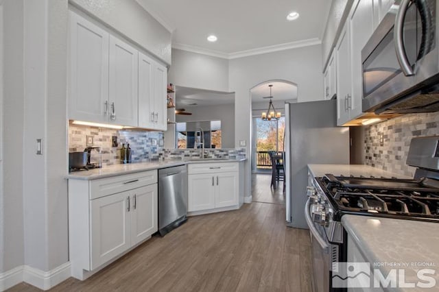 4531 Pyramid Peak Cir, Sparks, NV 89436 - kitchen with stainless steel appliances, a chandelier, white cabinetry, light wood-style floors, and crown molding