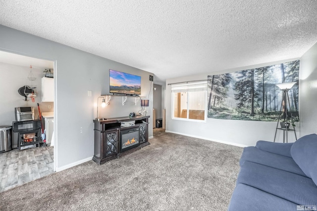 carpeted living room featuring a glass covered fireplace, a textured ceiling, and baseboards