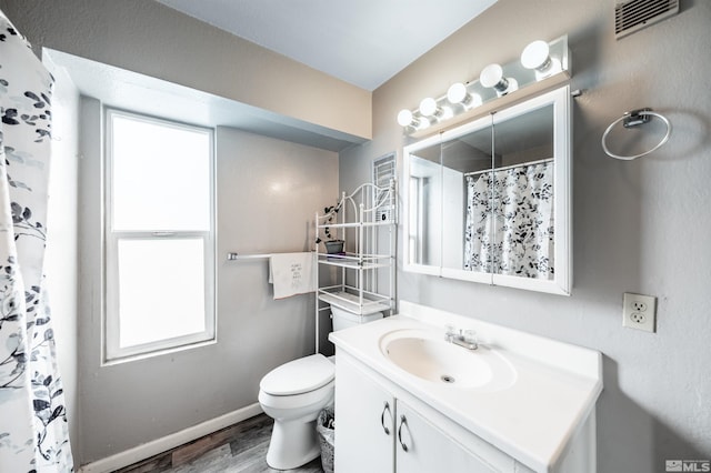 bathroom with wood finished floors, healthy amount of natural light, vanity, and baseboards