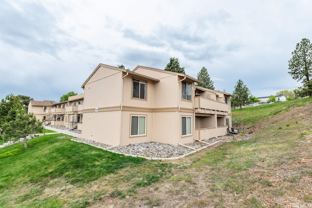 back of property with a yard and a balcony