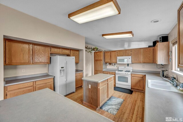 5620 Tassel Dr, Sun Valley, NV 89433 - kitchen with white appliances, light wood-style floors, light countertops, a sink, and a kitchen island