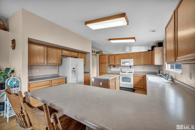 5620 Tassel Dr, Sun Valley, NV 89433 - kitchen featuring white appliances, a sink, a peninsula, light countertops, and brown cabinetry