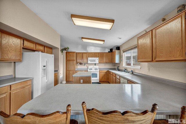 5620 Tassel Dr, Sun Valley, NV 89433 - kitchen featuring white appliances, lofted ceiling, a sink, a breakfast bar area, and a peninsula