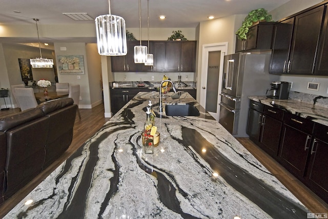 kitchen featuring a sink, a chandelier, light stone countertops, high quality fridge, and hanging light fixtures