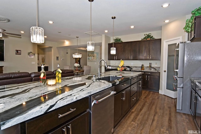 kitchen featuring open floor plan, a sink, dark wood finished floors, appliances with stainless steel finishes, and dark brown cabinets