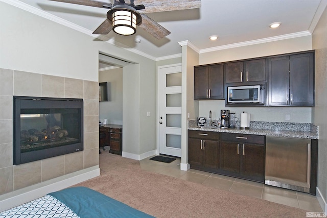 kitchen with stainless steel microwave, dark brown cabinets, a sink, baseboards, and crown molding