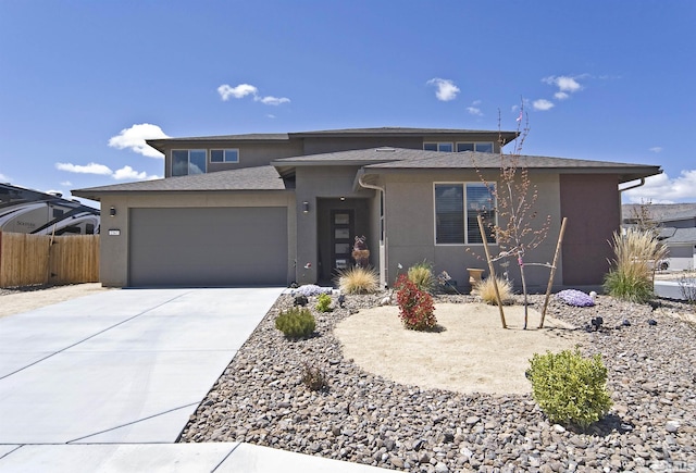 prairie-style house with stucco siding, an attached garage, fence, concrete driveway, and roof with shingles