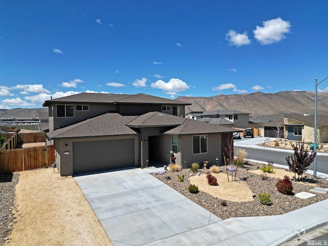 prairie-style home with a shingled roof, fence, stucco siding, and a mountain view