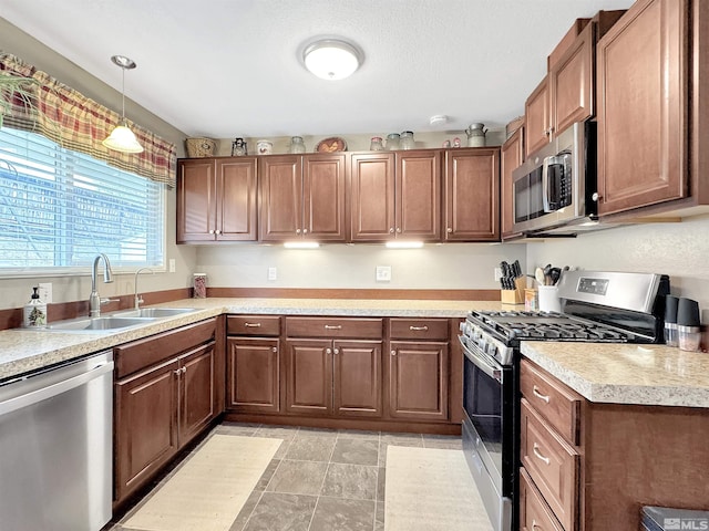 574 W National Ave, Winnemucca, NV 89445 - kitchen featuring stainless steel appliances, a sink, light countertops, decorative light fixtures, and brown cabinets