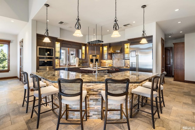 12360 High Vista Dr, Reno, NV 89511 - kitchen with stone tile floors, built in appliances, a spacious island, a breakfast bar area, and recessed lighting