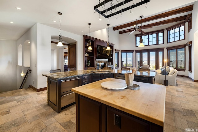 12360 High Vista Dr, Reno, NV 89511 - kitchen featuring stone tile floors, wooden counters, arched walkways, baseboards, and beamed ceiling
