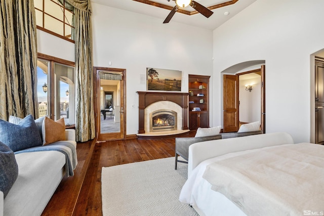 12360 High Vista Dr, Reno, NV 89511 - bedroom with a towering ceiling, arched walkways, hardwood / wood-style floors, a lit fireplace, and baseboards