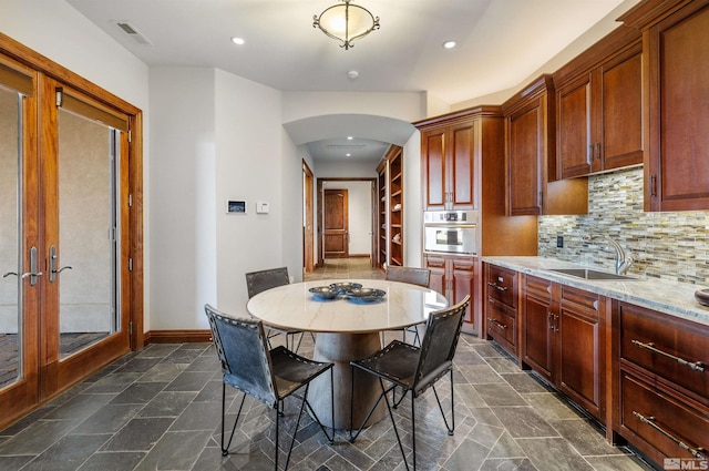 12360 High Vista Dr, Reno, NV 89511 - kitchen with a sink, arched walkways, oven, stone tile flooring, and tasteful backsplash