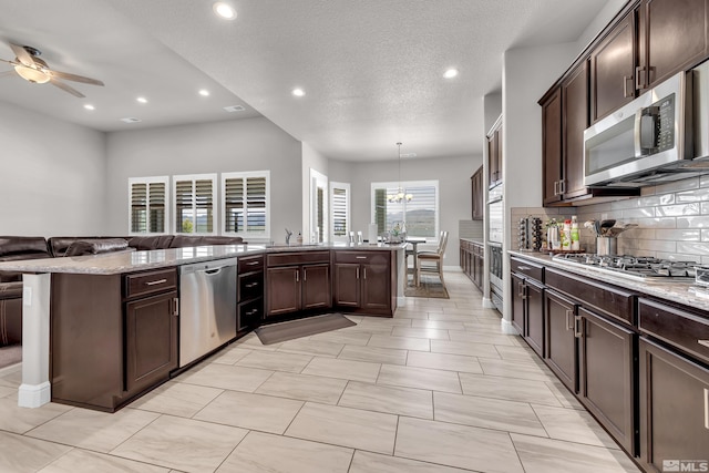 11641 Diamond Stream Dr, Sparks, NV 89441 - kitchen with appliances with stainless steel finishes, open floor plan, dark brown cabinets, a ceiling fan, and backsplash