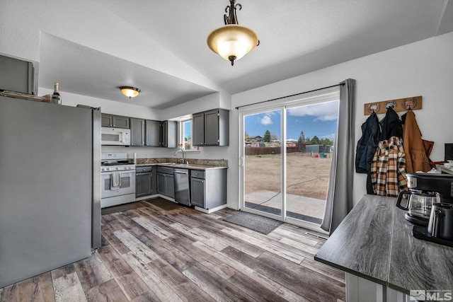 10205 Shenandoah Dr, Reno, NV 89508 - kitchen with stainless steel appliances, a sink, vaulted ceiling, gray cabinets, and dark wood-type flooring