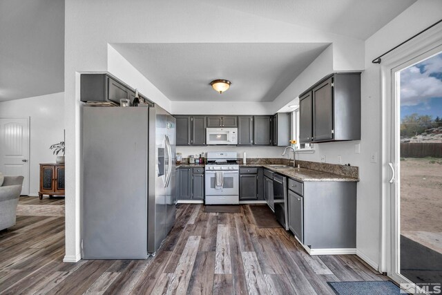 10205 Shenandoah Dr, Reno, NV 89508 - kitchen with appliances with stainless steel finishes, a sink, vaulted ceiling, dark wood-style flooring, and gray cabinets