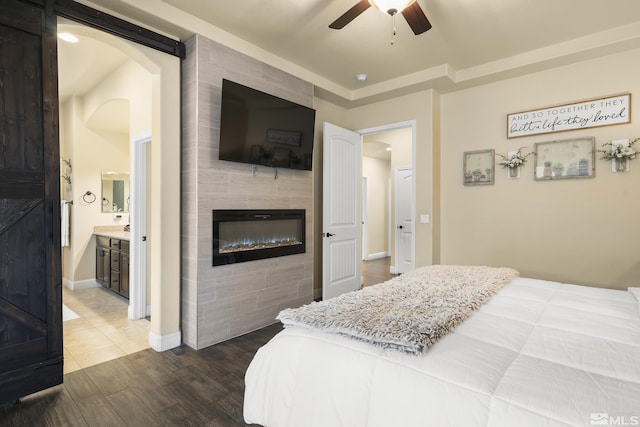 540 Clove Hitch Ct, Sparks, NV 89441 - bedroom featuring a tiled fireplace, dark wood-style flooring, arched walkways, baseboards, and connected bathroom