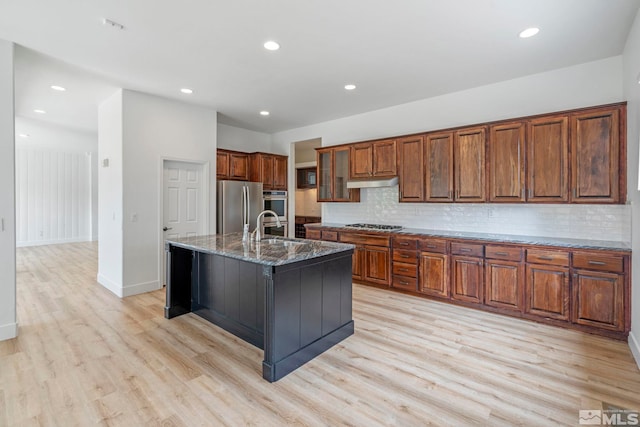 2705 Wind Feather Trl, Reno, NV 89511 - kitchen featuring appliances with stainless steel finishes, a sink, light wood-type flooring, brown cabinets, and decorative backsplash
