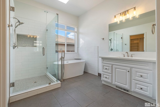 2705 Wind Feather Trl, Reno, NV 89511 - bathroom with tile patterned floors, a shower stall, vanity, a freestanding tub, and tile walls