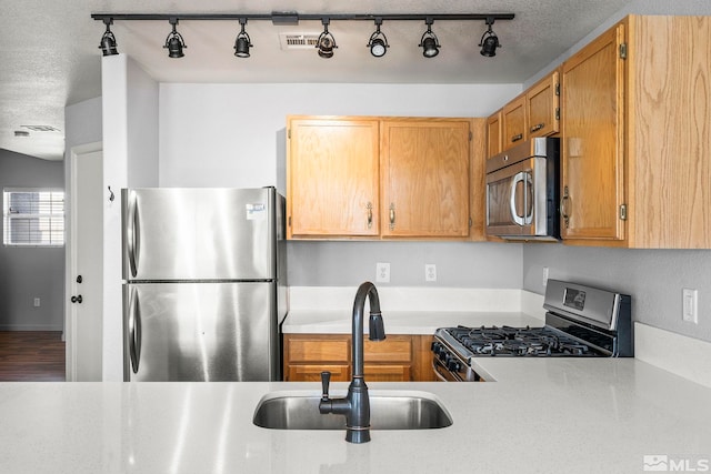 5645 Vista Luna Dr Apt 101, Sparks, NV 89436 - kitchen with appliances with stainless steel finishes, a sink, light countertops, rail lighting, and a textured ceiling