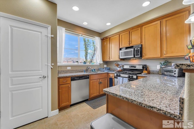 4889 Bougainvillea Cir, Sparks, NV 89436 - kitchen featuring appliances with stainless steel finishes, light stone countertops, brown cabinets, recessed lighting, and a sink