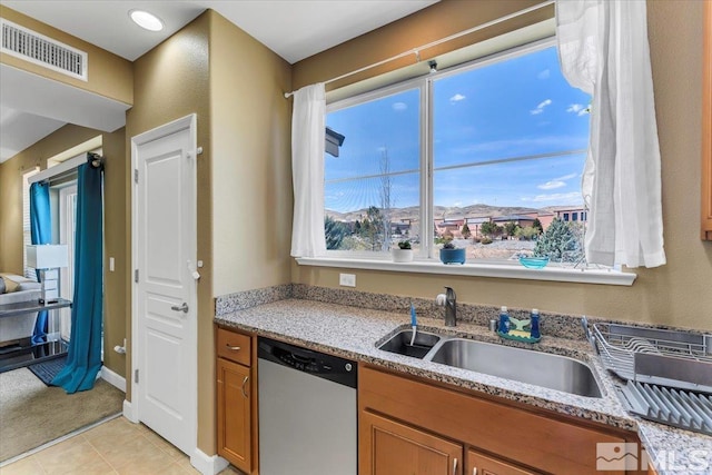 4889 Bougainvillea Cir, Sparks, NV 89436 - kitchen with stainless steel dishwasher, a sink, brown cabinetry, and light stone counters