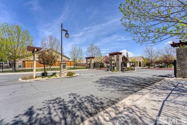 4889 Bougainvillea Cir, Sparks, NV 89436 - view of asphalt street with curbs, a gate, a gated entry, and street lighting