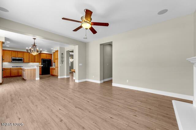 1095 S University Park Loop, Reno, NV 89512 - unfurnished living room featuring a chandelier, a ceiling fan, baseboards, and light wood finished floors
