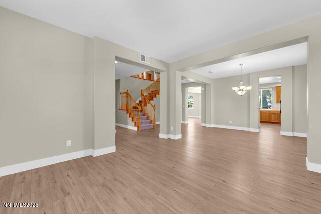 1095 S University Park Loop, Reno, NV 89512 - unfurnished living room featuring a chandelier, light wood finished floors, baseboards, and stairs